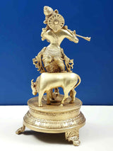 Brass Venugopala statue from side: Krishna with flute on cow, ornate base, 10 in