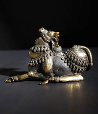 Small decorated Nandi idol in brass and stone, seated with ornate saddle and ornaments