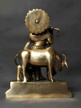 Brass Kanhaiya idol rear view, flute raised, bull at feet with raised base