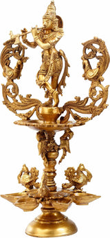 Gold-tone brass Krishna devotional lamp with standing deity and circular leaf trays