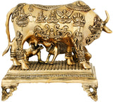 Brass cow sculpture close-up of deity reliefs on body and decorative base feet