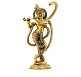 Brass Krishna statue holding flute, standing on ornate pedestal with serpent hood behind