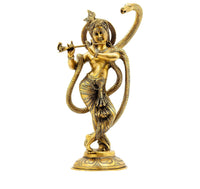 Brass Krishna statue holding flute, standing on ornate pedestal with serpent hood behind