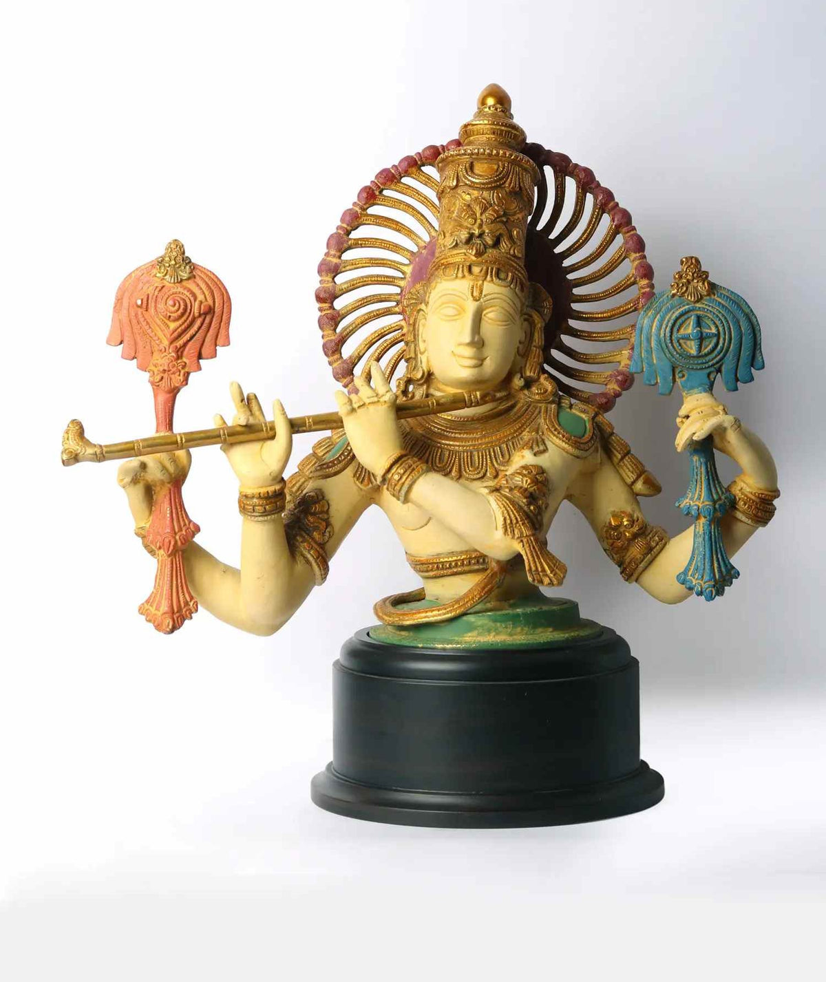 Colourful brass Krishna bust on black base, four-armed, flute, painted details