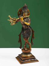 Brass Lord Krishna statue playing flute, ornate crown and jewelry, raised on square base
