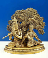 Brass Krishna and Radha flute statue, ornate tree canopy, kneeling pose on pedestal