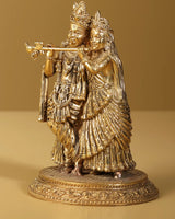 AONA gold brass Radha Krishna statue holding flute, detailed ornaments, round base