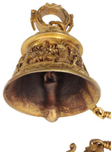 Brass temple bell underside with embossed deity scenes and hanging ring handle