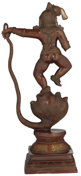 Brass Krishna statue defeating Kaliya, side view with raised arm and serpent tail