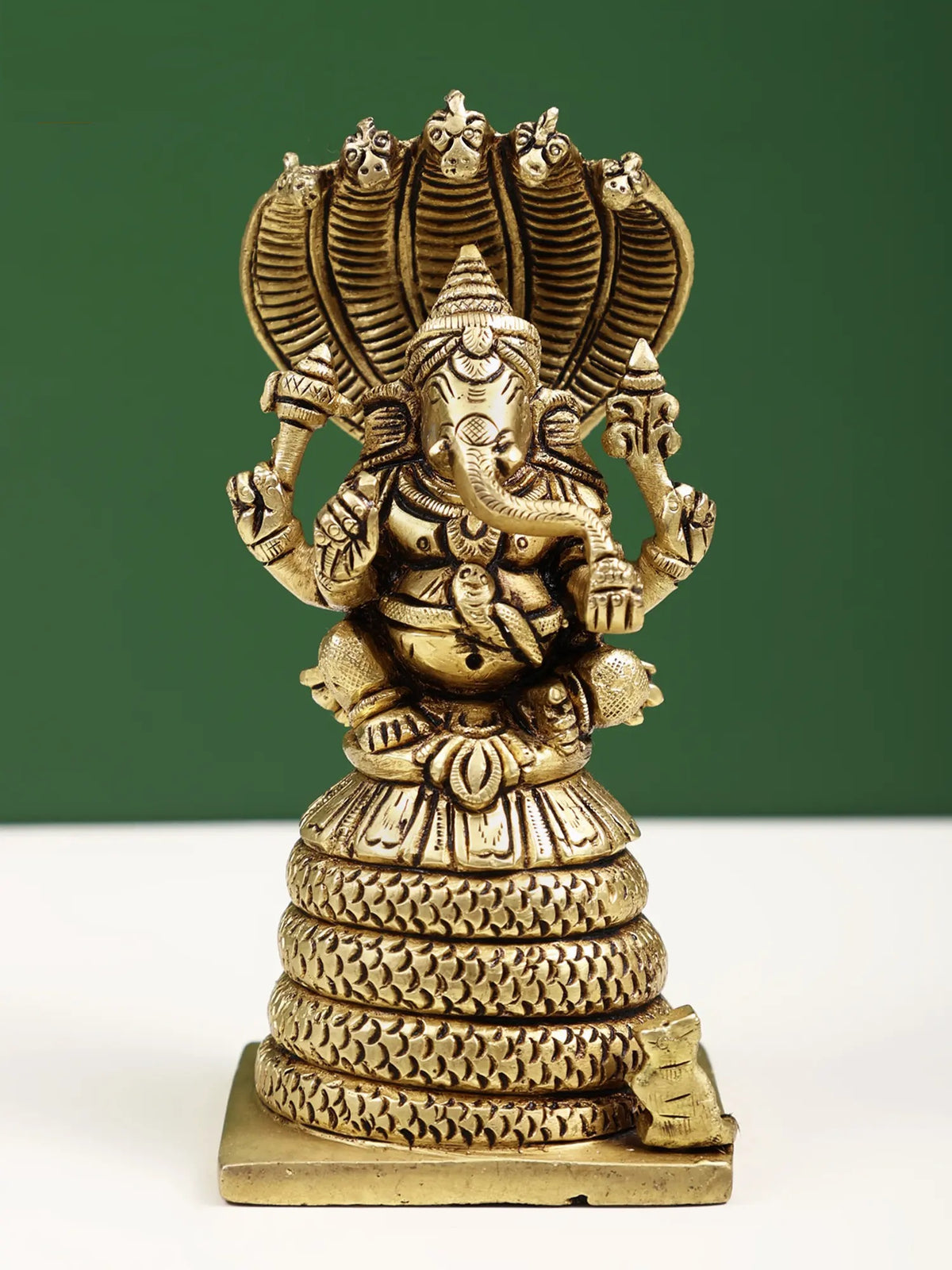 Small brass four-armed Ganesha statue seated on five-hooded serpent, 4 in