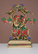 Brass Radha Krishna sculpture with jeweled tree, red and green accents on pedestal