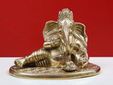 Brass Ganesha idol enjoying modak, seated on engraved round pedestal