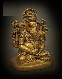 Brass Ganesha deity figure with crown and side-held props, seated on round base
