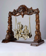 Brass Radha-Krishna figures seated on wooden swing with carved top and chains
