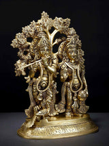 Gold-toned brass Radha and Krishna figurines with carved tree canopy, standing