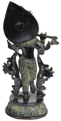 Brass Krishna figurine playing flute, side view with crown and green-gold details