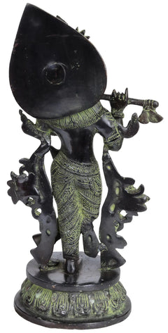 Brass Krishna figurine playing flute, side view with crown and green-gold details