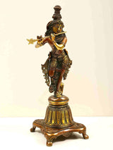 Brass Lord Krishna figurine on raised pedestal, gold flute and ornate attire