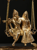 Radha und Krishna als goldfarbene Sitzfiguren auf der Schaukel, an Ketten hängend