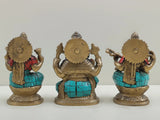 Back view of inlaid brass trio idols, seated on lotus with red and turquoise accents