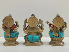 Back view of inlaid brass trio idols, seated on lotus with red and turquoise accents