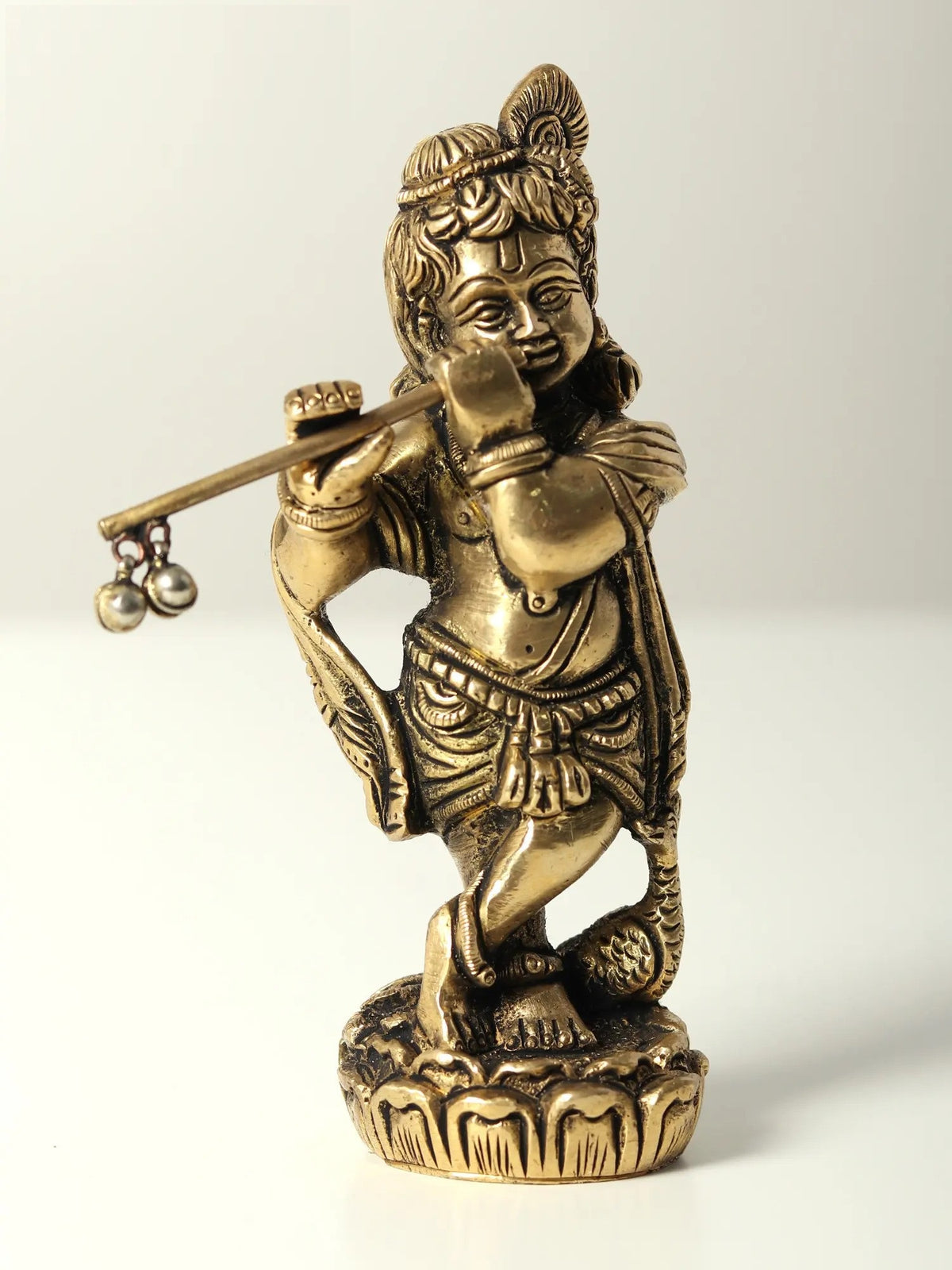 Small brass idol of Bal Krishna playing flute, standing with detailed face and jewelry