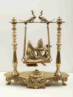 Brass peacock-perched swing statue of Radha and Krishna on ornate carved stand