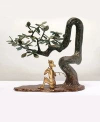 Standing brass Lord Krishna flute statue on base beneath arched leafy branches