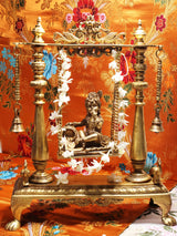 Brass Krishna swing idol with colorful headdress and white flower garland