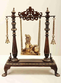 Butter Krishna brass swing display with seated deity, gold chains, twin bell accents