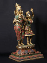 Krishna playing flute with Radha, raised arms, ornate patterned outfits, stonework base