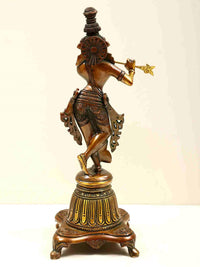 Rear view: brass Lord Krishna statue on high pedestal, flute raised, detailed back
