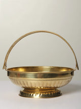 Brass pooja flowers basket with arched handle, shallow bowl and decorative base.