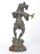 Lord Krishna flute-playing figurine, side view, dark metal with gold details, on base