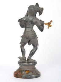 Lord Krishna flute-playing figurine, side view, dark metal with gold details, on base