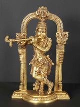 Brass Krishna statue playing flute with ornate kirtimukha arch, 13 inches