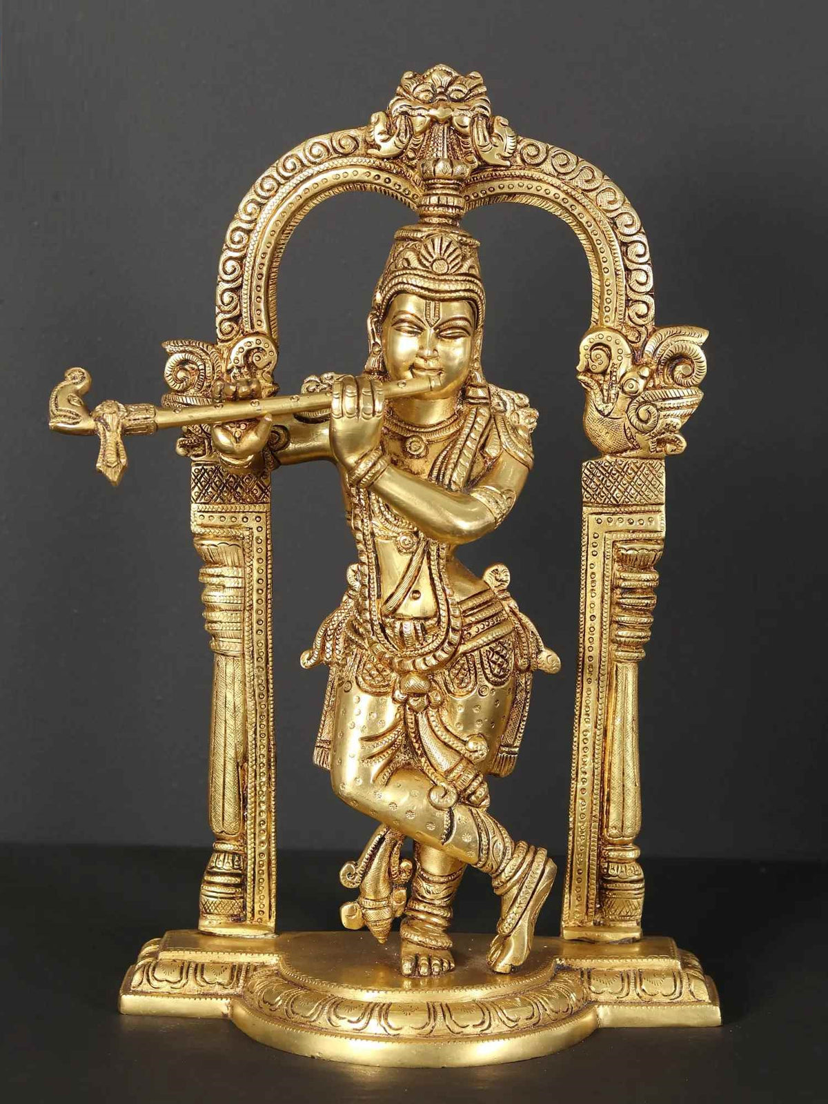 Brass Krishna statue playing flute with ornate kirtimukha arch, 13 inches