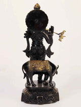 Rear view of black and gold brass Venugopal statue, playing flute on cow