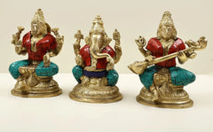 Lakshmi, Ganesha and Saraswati brass idol trio with raised hands, red tunics, teal base