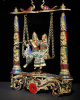 Brass Radha-Krishna swing statue with colorful inlay on pedestal pillars and chain swings