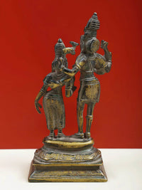 Brass Shiva and Parvati deity statue with detailed outfits and raised hands on base
