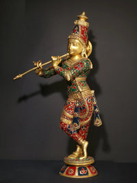 Standing Krishna brass statue holding flute, ornate red-green inlay on outfit