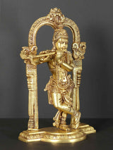 Brass Krishna statue playing flute, detailed face and jewelry, within arched frame