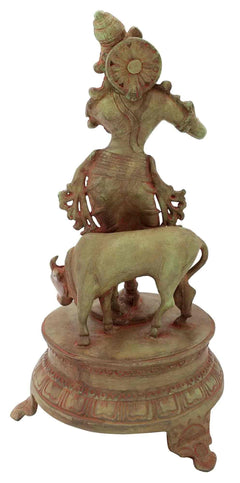 Venugopala brass idol rear view, seated on small animal, green-gold finish, on round base