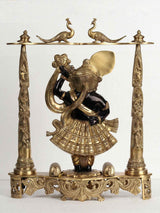 Brass deity statue in turned pose, black-and-gold attire, ornate pedestal, 18-inch height