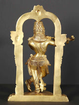 Back view brass Krishna statue playing flute with kirtimukha arch ornament