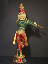 Rear view Krishna brass statue, red-green inlay garments and raised flute arm