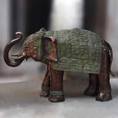 Large brass elephant sculpture, side view with detailed green patina armor and curled tail
