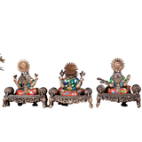 Back view of brass Ganesha, Lakshmi, and Saraswati idols on ornate painted pedestals
