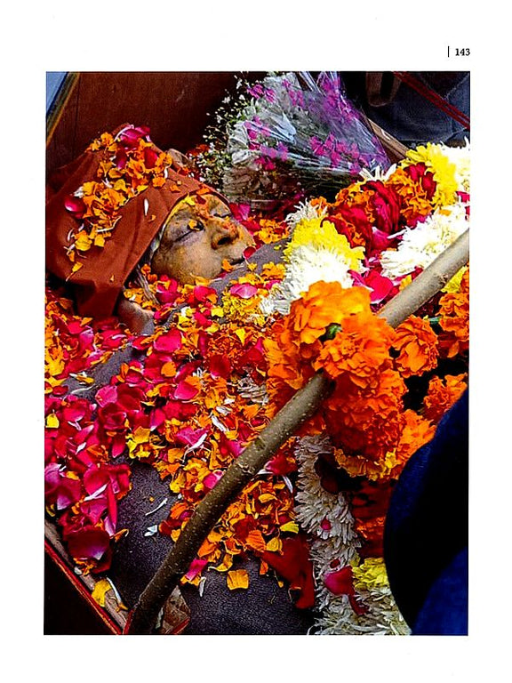Temple offering page with garlands and flowers surrounding a decorated idol and staff